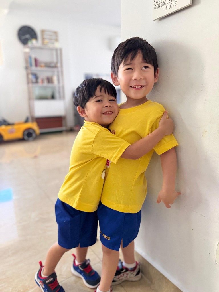 Two young brothers hugging and smiling indoors.